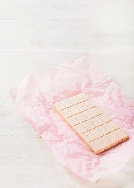 Chocolat blanc sur papier rose sur fond texturé