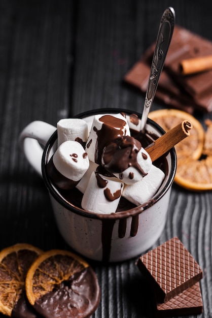 Chocolat chaud avec un bâton de cannelle et des tranches d'orange séchées à la guimauve