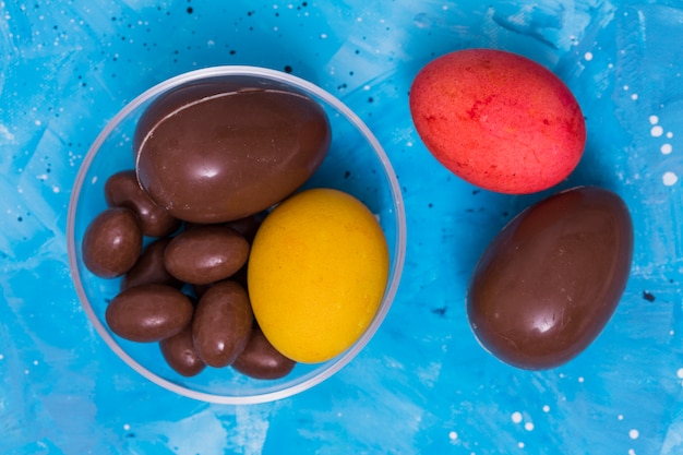 Chocolat et oeufs de Pâques colorés sur la table bleue