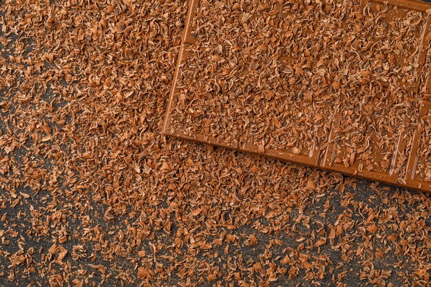 Chocolat râpé avec barre de choco à plat sur un fond sombre