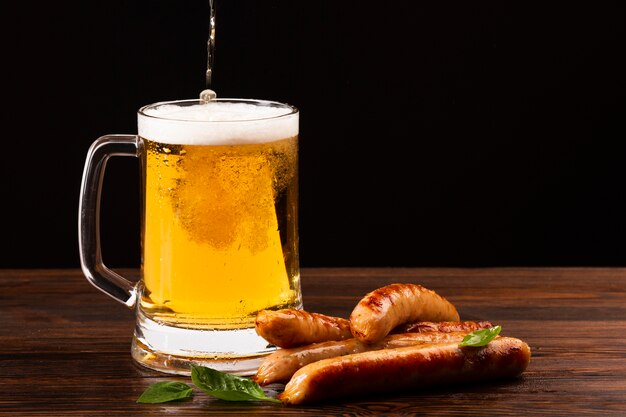 Chope de bière vue de face avec des saucisses