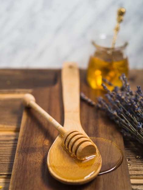 Chope de miel sur une cuillère en bois sur la planche à découper