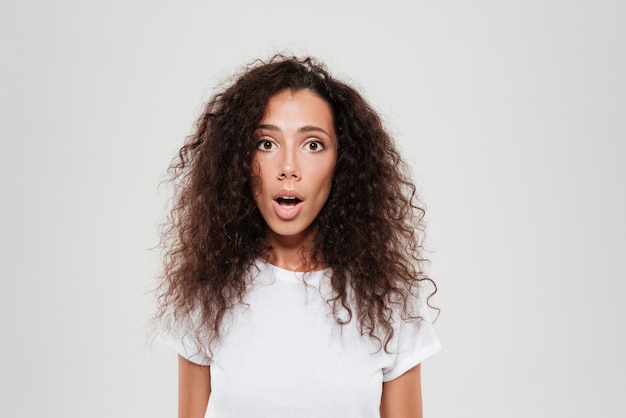 Choqué femme bouclée en regardant la caméra