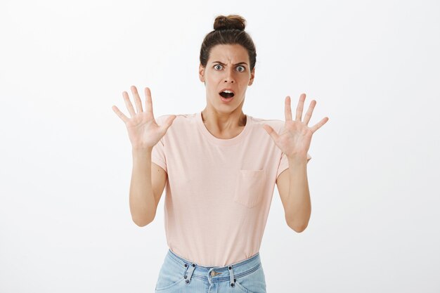 Choqué jeune femme élégante posant contre le mur blanc