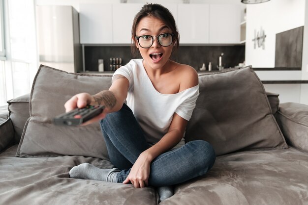 Choqué jeune femme excitée regarder la télévision.