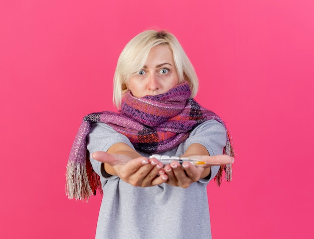 Photo gratuite choqué jeune femme slave malade blonde portant un foulard détient des paquets de pilules médicales