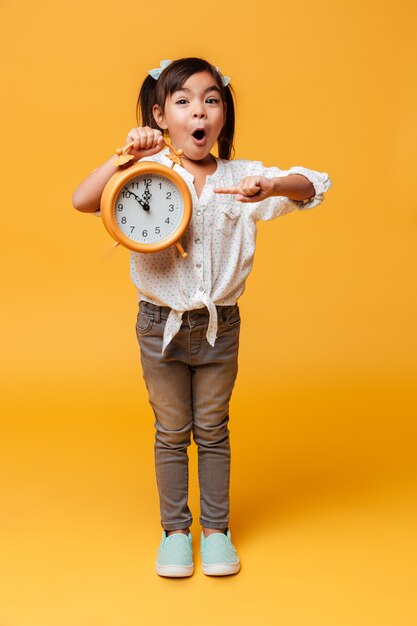 Choqué petite fille enfant tenant réveil.