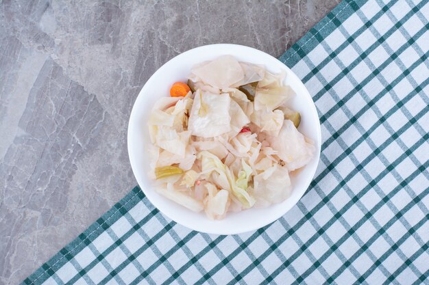 Chou blanc mariné dans un bol blanc avec nappe.