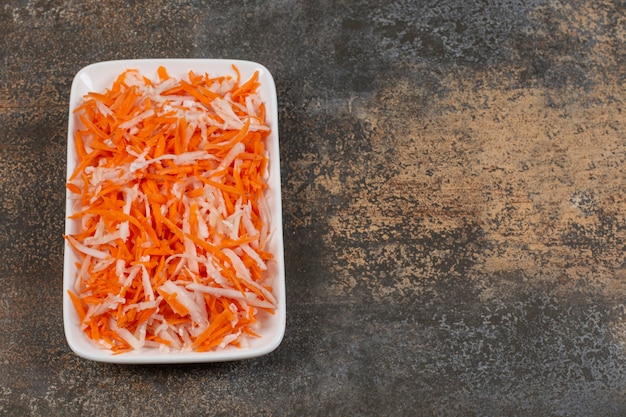 Chou et carottes en julienne savoureux sur plaque blanche.