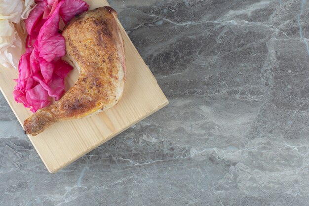 Chou fermenté avec poulet grillé sur planche de bois.