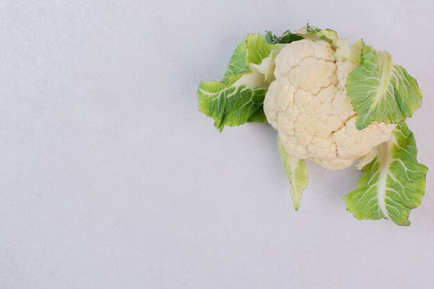 Chou-fleur frais avec des feuilles sur une surface blanche