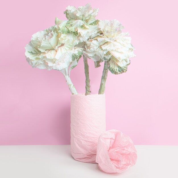 Chou ornemental dans un vase, enveloppé de papier rose sur mur rose