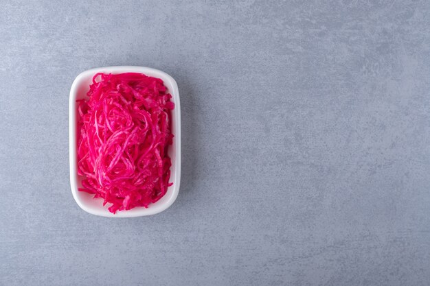 Le chou rouge fermenté se trouve dans un bol , sur le fond de marbre.