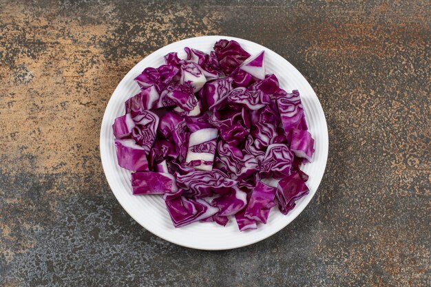 Chou rouge finement haché dans l'assiette sur la surface en marbre