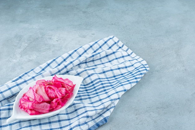 Choucroute fermentée rouge hachée dans un bol sur un dessous de plat , sur la table bleue.