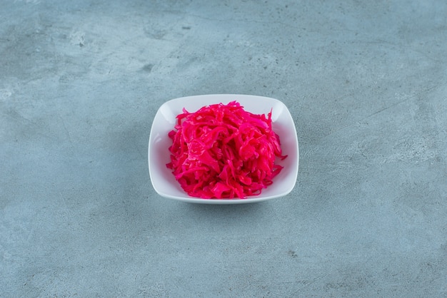 Choucroute fermentée rouge hachée savoureuse dans un bol , sur la table bleue.