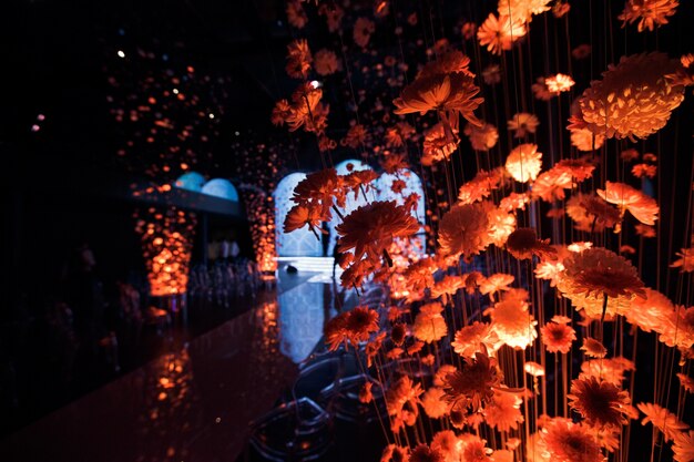 Les chrysanthèmes éclairés avec de la lumière orange s&#39;accrochent aux fils dans le hall
