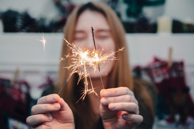 Cierges magiques brûlants dans les mains d'une jeune femme dans l'obscurité