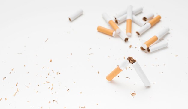 Cigarette et tabac cassés au-dessus d&#39;une surface blanche