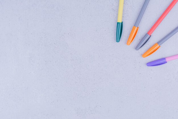 Cinq crayons de gel multicolores isolés sur une surface grise