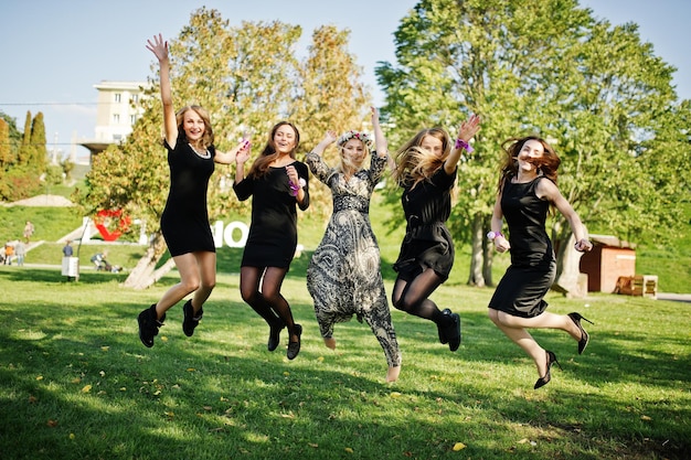 Cinq filles portent du noir sautant à la fête de poule
