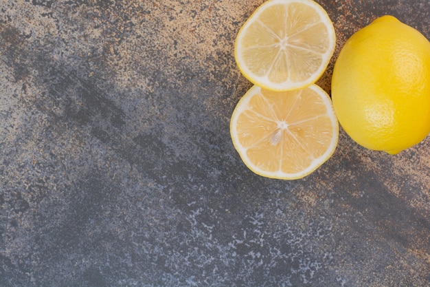 Un citron entier avec des tranches sur la surface de la pierre