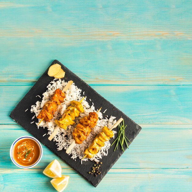 Citron et sauce près de la planche avec brochette de poulet