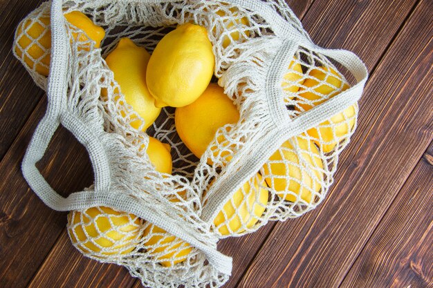 Citrons dans un sac en filet à plat sur une table en bois