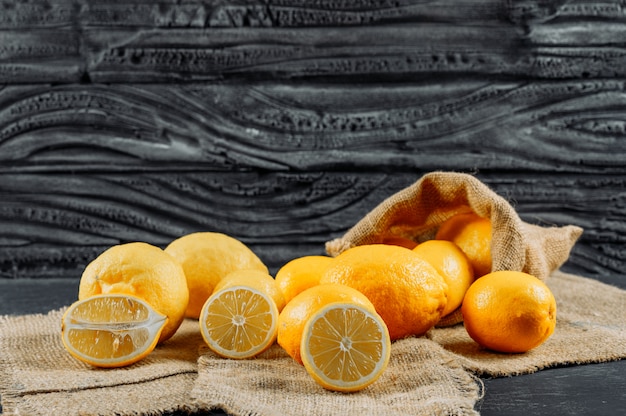 Citrons dans une vue latérale du sac sur un tissu et un espace de fond sombre pour le texte