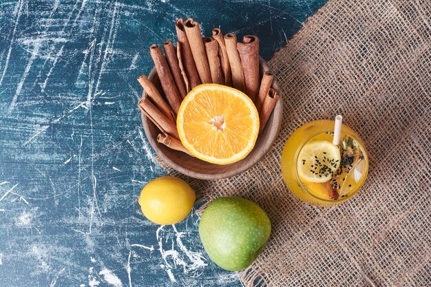 Citrons et épices avec une tasse de boisson sur bleu.