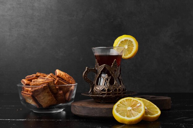 Citrons isolés sur une planche de bois avec des craquelins et un verre de thé.