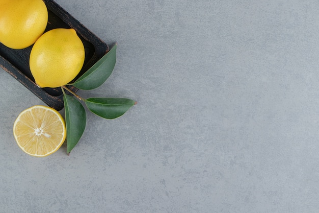 Citrons juteux sur un petit plateau orné de feuilles sur marbre