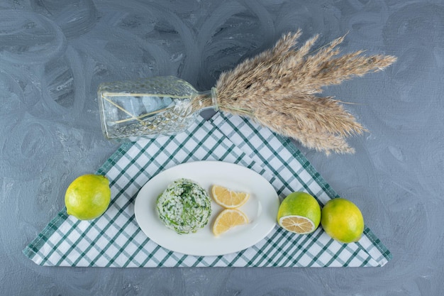 Citrons, riz cuit et tiges décoratives sur nappe pliée sur table en marbre.