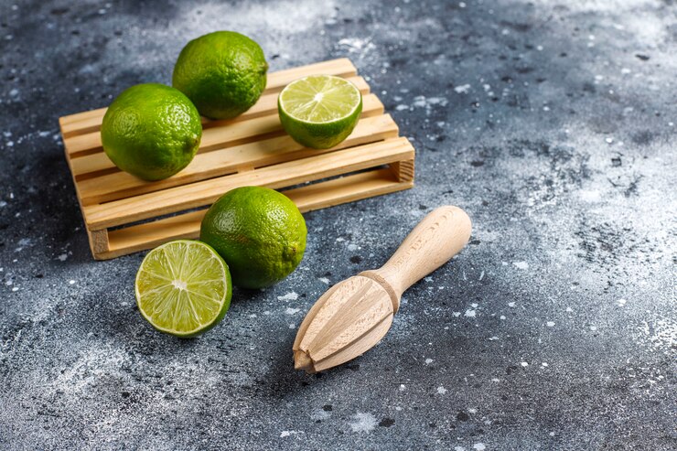 Photo gratuit citrons verts frais avec du jus d'agrumes en bois