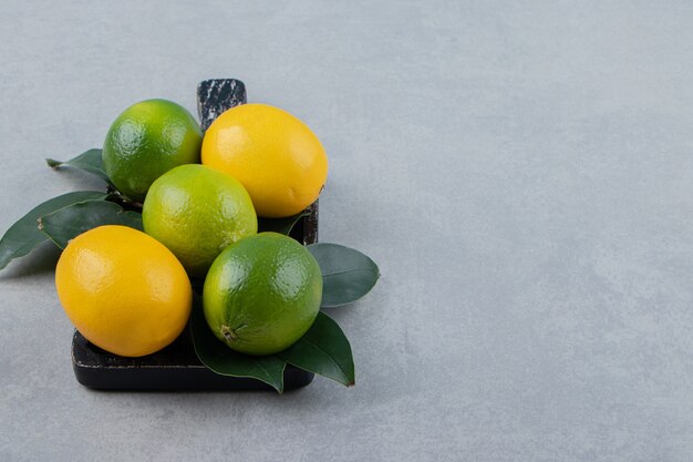 Citrons verts et jaunes sur une planche à découper noire
