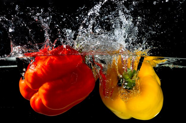 Éclaboussures de poivrons rouges et jaunes dans l&#39;eau claire