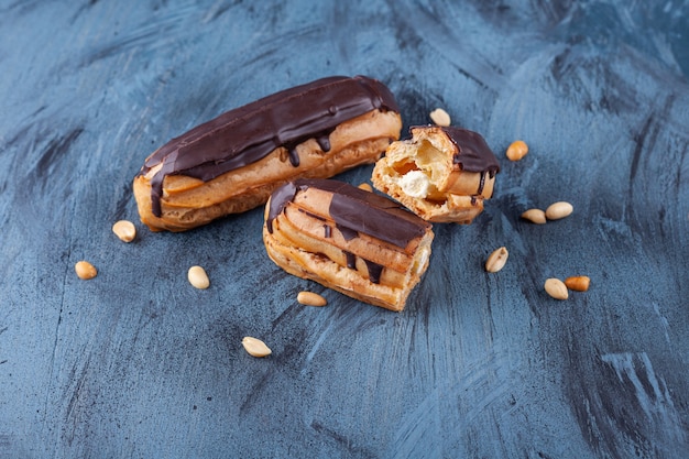 Éclairs au chocolat croustillant fraîchement cuits avec des noix placées sur une surface colorée.