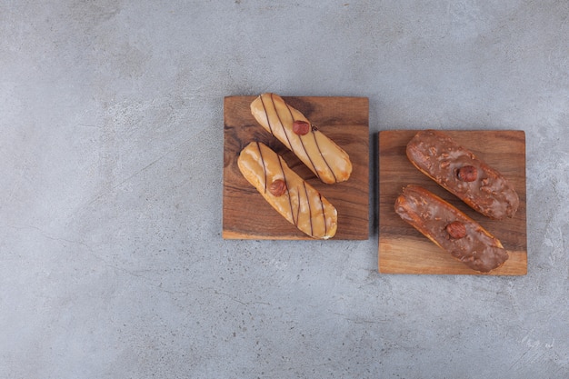 Éclairs français traditionnels au chocolat placés sur planche de bois.