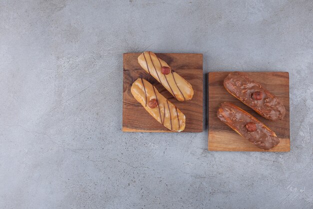 Éclairs français traditionnels au chocolat placés sur planche de bois.