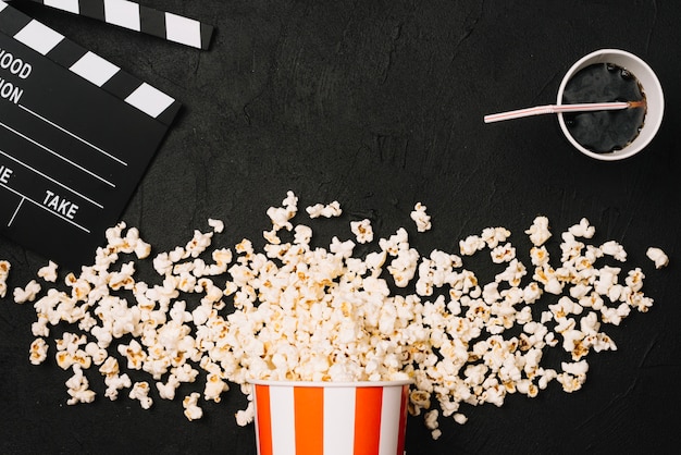 Photo gratuite clapperboard et cola près de pop-corn renversé