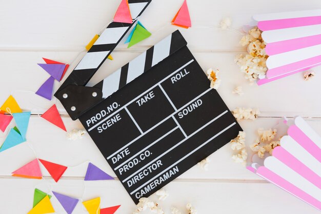 Clapperboard près de la guirlande de fanion et du maïs soufflé