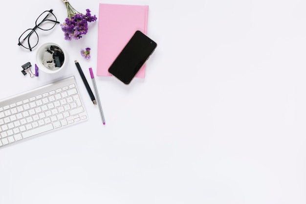 Clavier blanc et téléphone portable avec papeterie sur fond blanc