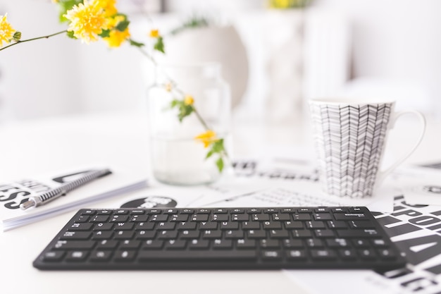 Photo gratuite clavier avec des fleurs jaunes et une tasse