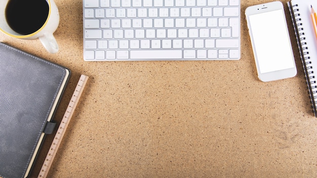 Photo gratuite clavier et smartphone près de la papeterie et des boissons