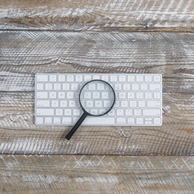 Clavier vue de dessus avec loupe sur fond en bois. verticale