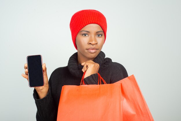 Client sérieux en pull d'hiver et chapeau tenant des sacs à provisions