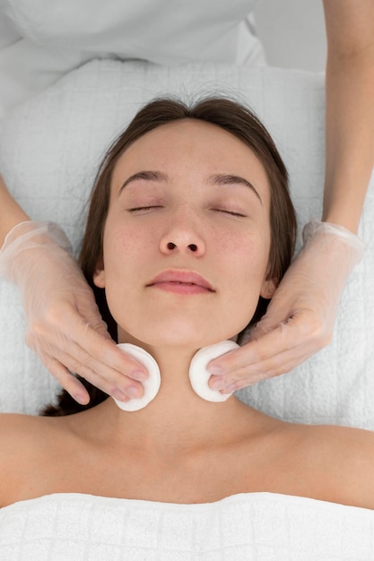 Cliente au salon pour la routine de soins du visage avec des disques de nettoyage