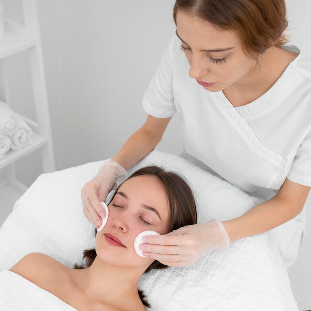 Cliente au salon pour la routine de soins du visage avec des disques de nettoyage