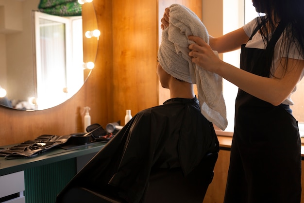 Photo gratuite une cliente se fait sécher les cheveux chez le coiffeur.