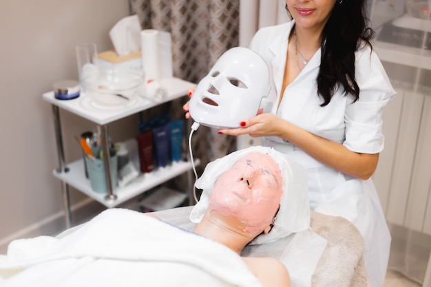 Photo gratuite la cliente se trouve dans le salon sur la table de cosmétologie avec un masque blanc sur son visage